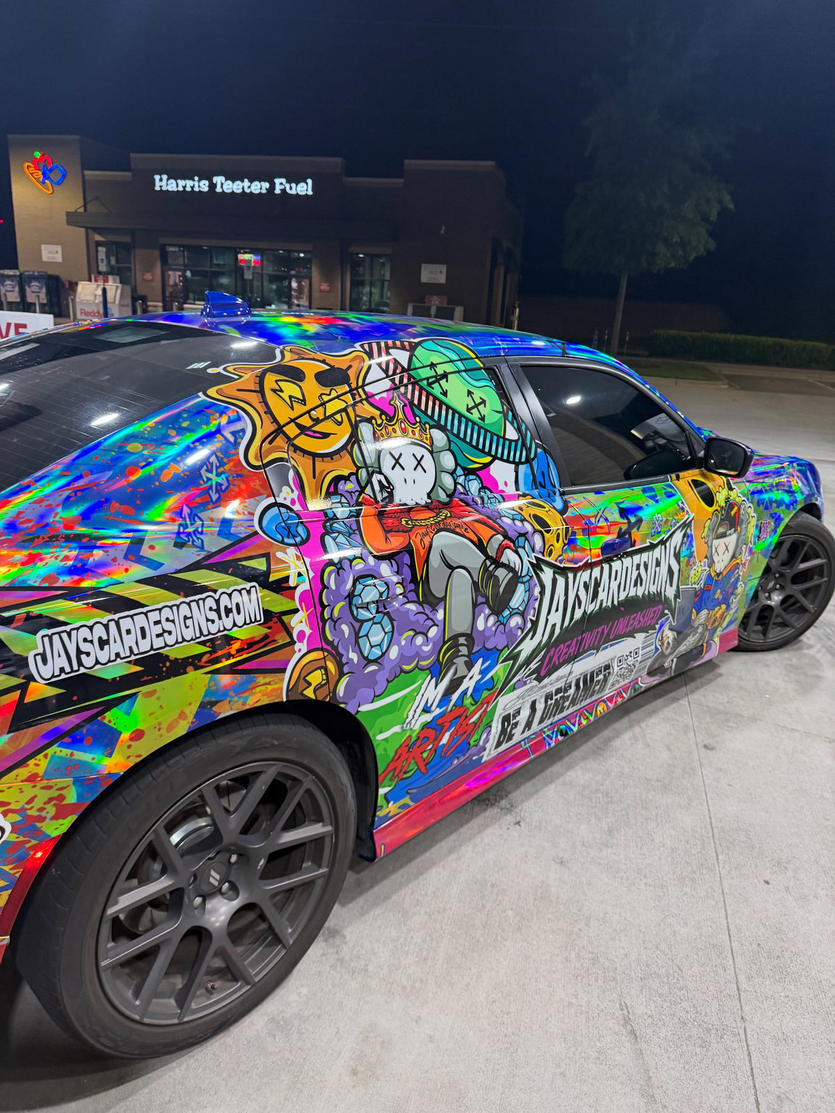 Printed holographic show wrap with hand-drawn characters on the side of a Dodge Charger